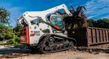 Гусеничный мини погрузчик Bobcat Т870 загружает контейнер